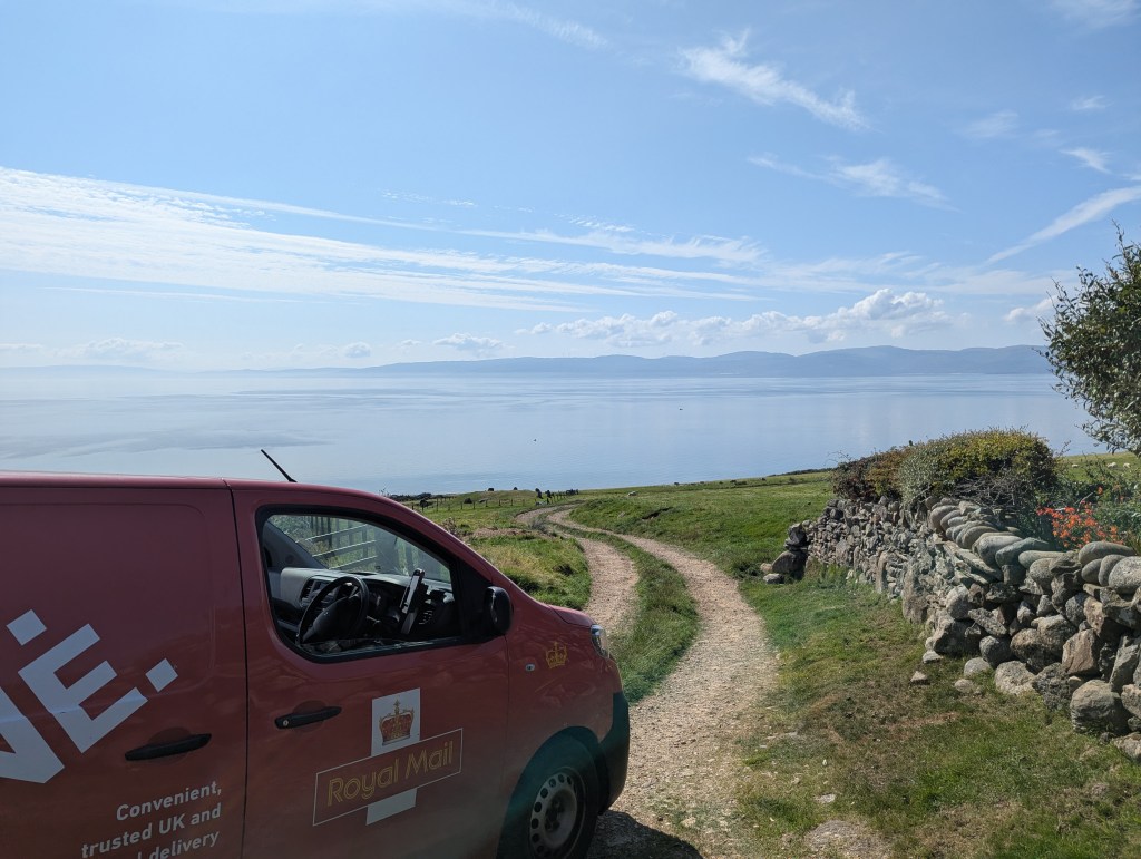 A photo of my Royal Mail van on a farm track, with the sea in the distance